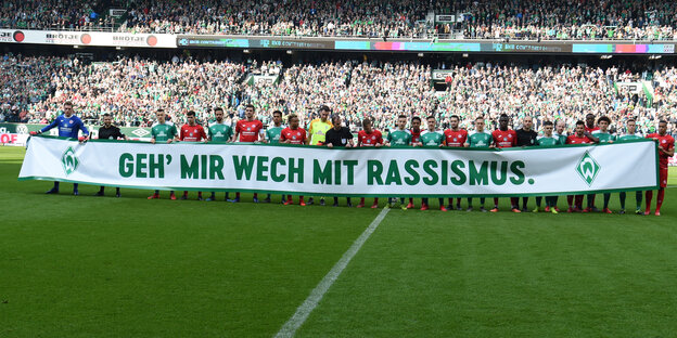 Werder-Bremen-Spieler halten im Stadion einen Banner mit der Aufschrift: "Geh' mir wech mit Rassismus"