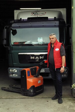 Älterer Herr steht vor LKW und guckt skeptisch Älterer Herr steht vor LKW und guckt skeptisch