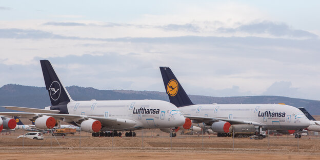 zwei Airbus-A380-Flugzeuge nebeneinaner auf brauner Erde er