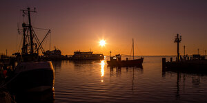 Ein Kutter fährt kurz nach Sonnenaufgang in den Hafen der Insel Hiddensee.