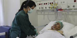 Eine Pflegerin steht am Krankenbett der 116-Jährigen Ayse Karatay