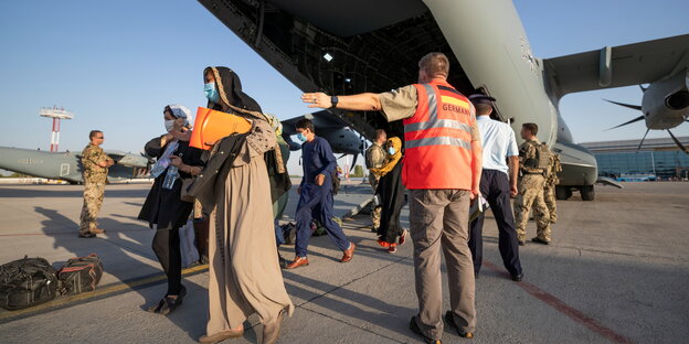 Menschen steigen auf dem Flughafen in Taschkent aus einem Flugzeug der Bundeswehr