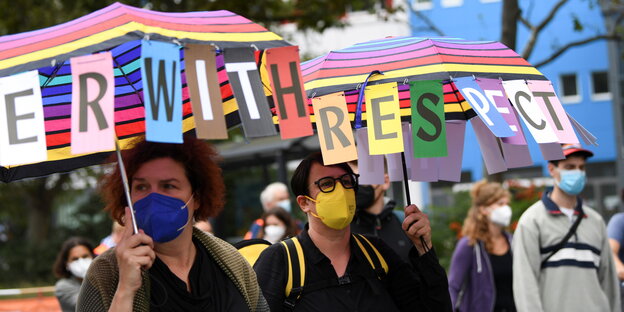 Zwei Frauen mit bunten Regenschirmen und Maske auf der Unteilbar-Demo in Berlin