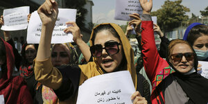 Frauen auf einer Straße in Kabul mit Schildern