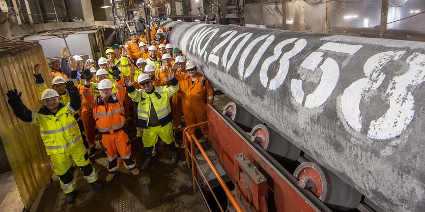 Mitarbeiter der Nordstream 2 stehen ine einem Verlegekranschiff mit Helmen und Schutzanzügen