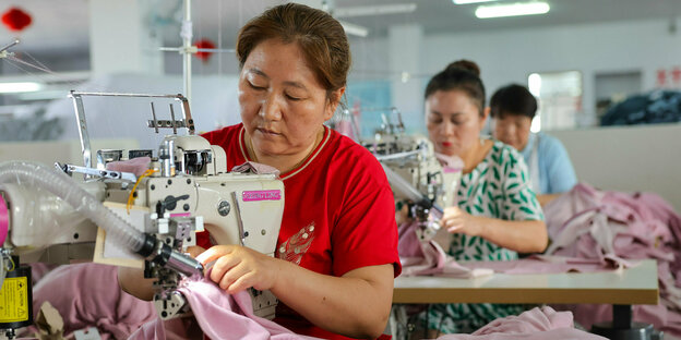 Frauen sitzen an Nähmaschinen und arbeiten in einem Bekleidungsunternehmen in Nordwestchinas Autonomer Region Xinjiang