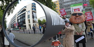 Ein Demonstrant schaut durch eine riesige Fernrohrattrappe