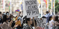 Eine asiatisch gelesene Person hält ein Schild in der Hand mit der Aufschrift "Passive Asians my a*se!"