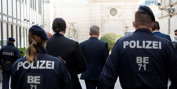Rücken von einer Personengruppe bestehend aus polizei und einem Mann im Anzug