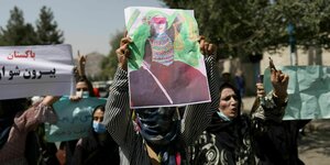 Eine Gruppe von Frauen bei einer Demo in Kabul. Eine hält ein Plakat mit der Figur der Justitia