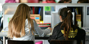 Zwei Schülerinnen sitzen in einer Schulbank