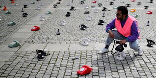 Ein Mann mit einer Weste plaziert alte Telefone auf den Boden