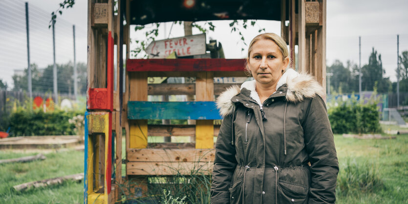 Eine Frau in Winterjacke steht vor einem bunten Holzgerüst