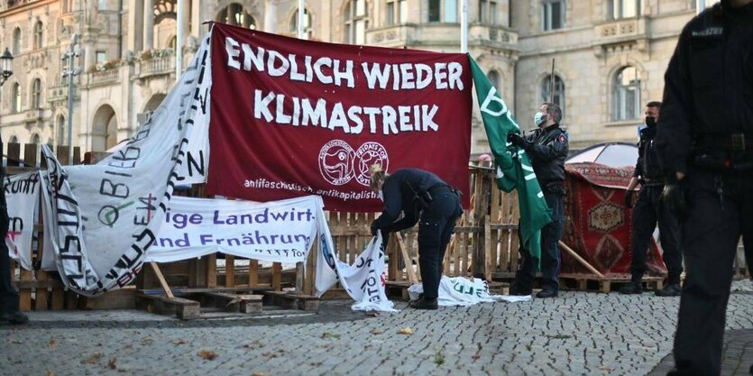 Polizisten hängen Banner des Klimacamps ab, auf einem roten in der Mitte steht: "Endlich wieder Klimastreik"