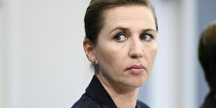 Mette Frederiksen sieht mit ernsten Blick an der Kamera vorbei