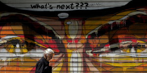 Eine Frau geht vor einem Grafitti „What's next???“