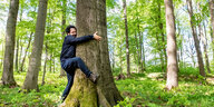 Fahri Yardım umarmt einen Baumstamm