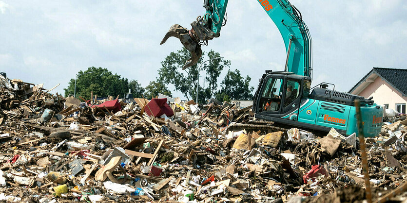 Ein Bagger in einem Müllberg voller Schrott durch die Flut