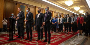 Mehrere Politiker stehen in Bukarest mit einer Maske auf einem Teppich.