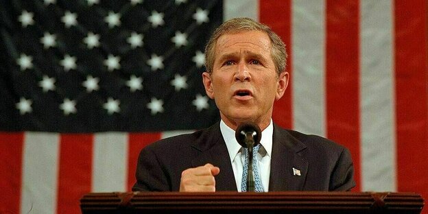George W. Bush steht an einem Rednerpult vor der Flagge der Vereinigten Staaten