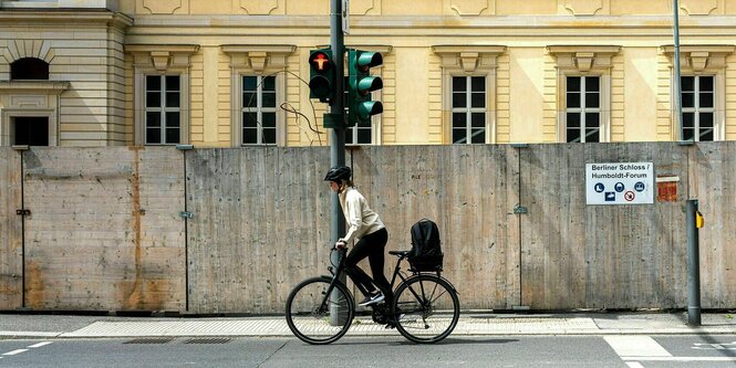 Eine Radfahrerin mit Helm fährt an einer Ampel vorbei