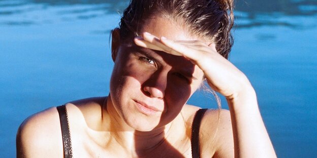 Porträt von Calla Henkel, ise schirmt mit der Hand die Augen gegen die Sonne ab.