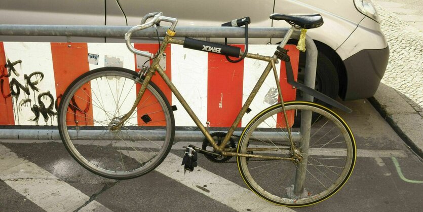 Ein abgenutztes Fahrrad ist an einer Absperrung angekettet