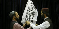 Zwei Männer arrangieren eine Taliban-Flagge
