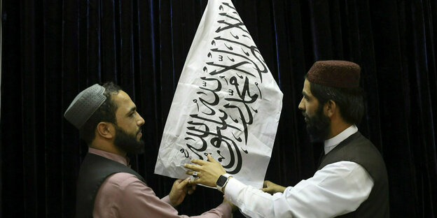 Zwei Männer arrangieren eine Taliban-Flagge