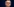 Close-up eines älteren Mannes mit Brille vor blauem Hintergrund, er schaut ernst.