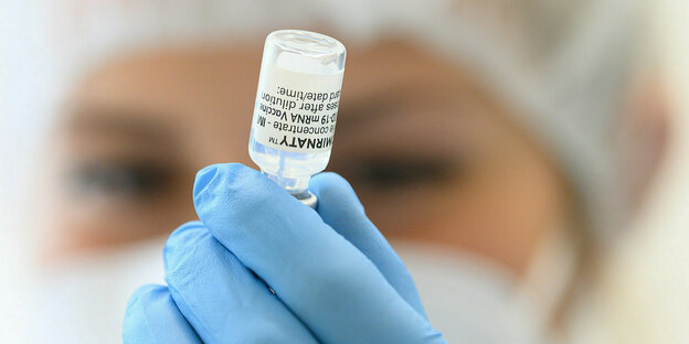 Eine medzinische Mitarbeiterin zeigt ein Fläschchen Impfstoff vor die Kamera