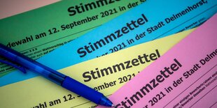 Musterbögen für Stimmzettel in verschiedenen Farben liegen auf einem Tisch.