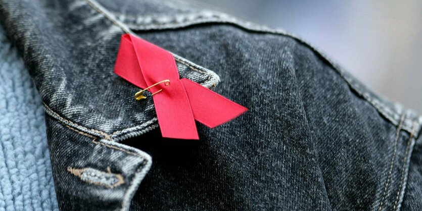 Rote Aids-Schleife am Kragen einer Jeansjacke