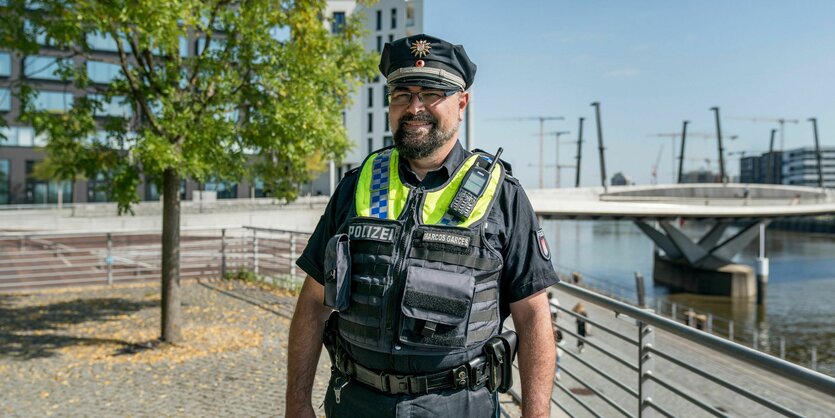 Polizist in schwarzer Uniform mit gelber Weste steht am Kai