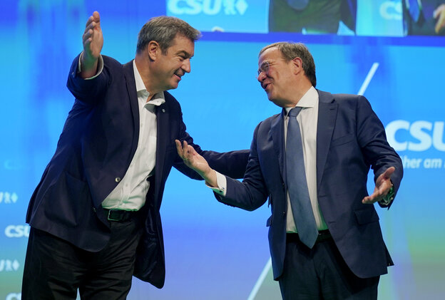 Markus Söder und Armin Laschet stehen nebeneinander und berühren sich in einer Art halben Umarmung