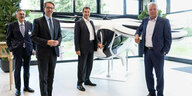 vier Herren stehen vor dem Model eines Fugtaxis von Airbus