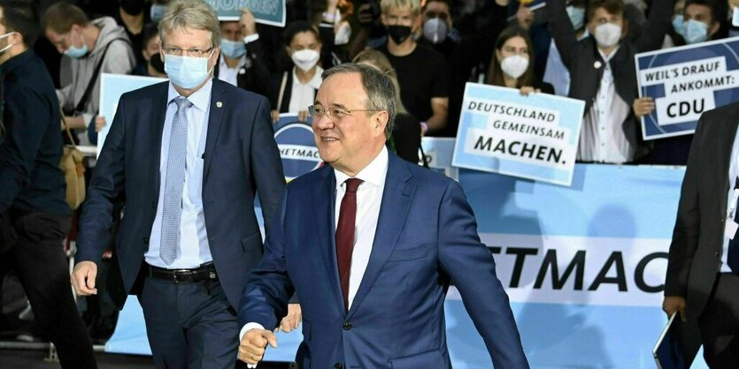 Arnim Laschet auf dem Weg zum Triell, hinter ihm stehen AnhängerInnen mit Plakaten und feuern Laschet an