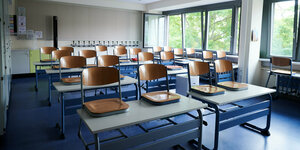 Stühle stehen in einem Klassenzimmer auf den Tischen