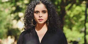 Rana Ayyub steht im Grünen und blickt in die Kamera