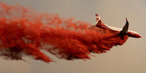 Ein Flugzeug wirft eine rote Substanz vom Himmel