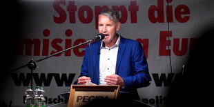 Björn Höcke steht an einem Rednerpult auf dem der Schriftzug PEGIDA aufgedruckt ist