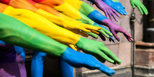 Hände in Regenbogenfarben bemalt ausgestreckt während dem CSD in Frankfurt