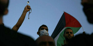 Ein Mann hält eine palästinensische Flagge und einen Löffel in die Höhe