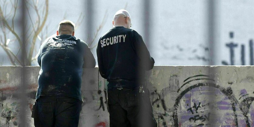 Zwei Securitymänner stehen an ein Mäuerchen gelehnt