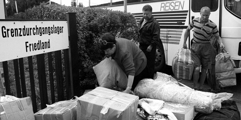 Menschen tragen Kartons mit ihrem Besitz aus einem Reisebus