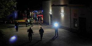 Menschen mit Taschenlampen im Dunkeln vor einem großen Gebäude