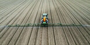 Mit einem Traktor wird Plfanzenschutzmittel auf ein karges Feld aufgesprüht