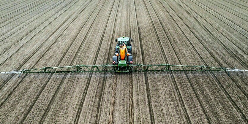 Mit einem Traktor wird Plfanzenschutzmittel auf ein karges Feld aufgesprüht