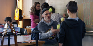 Der Lehrer Herr Bachmann jongliert im Klassenzimmer vor einem seiner Schüler.