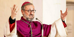 Erzbischof Heße predigt mit geöffneten Armen in die Höhe gereckt in der Kirche